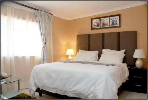 sypialnia z dużym białym łóżkiem i oknem w obiekcie Peace & Lovely Bed and Breakfast w mieście Johannesburg