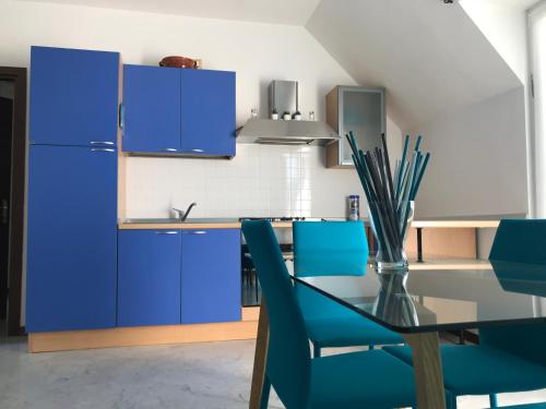 eine Küche mit blauen Schränken sowie einem Tisch und Stühlen in der Unterkunft La Magnolia Apartments in Desenzano del Garda