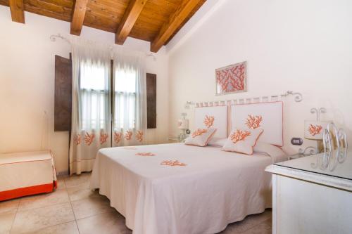 1 dormitorio blanco con 1 cama blanca grande con almohadas rosas en B&B Monte Prama, en Cabras