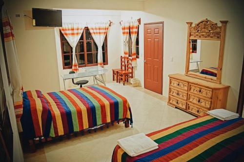 Un dormitorio con dos camas y un escritorio y un espejo. en HOTEL SAN JUDAS, en San Pablo Villa de Mitla