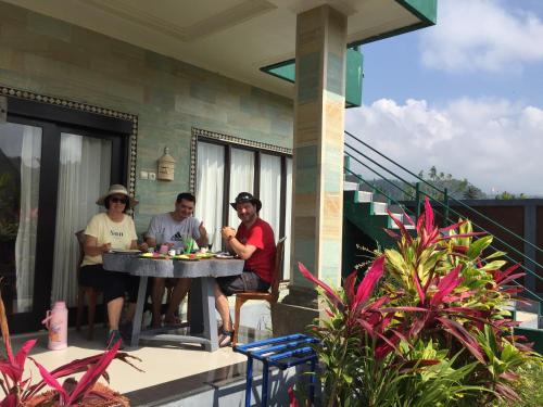 a group of people sitting at a table on a porch at GumiBali Villa in Tirtagangga