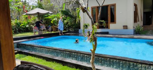 a woman standing in a swimming pool next to a house at Medewi Beach Inn in Pulukan