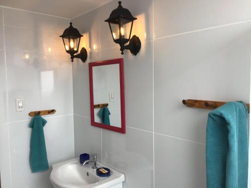 a bathroom with a sink and a mirror and lights at Cruz del Sur in Pucusana