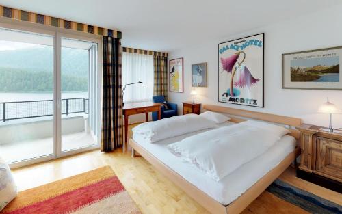 a bedroom with a large bed and a large window at Traunter Via in St. Moritz