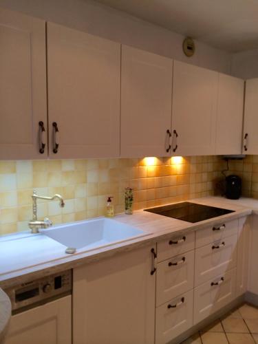 une cuisine avec des armoires blanches et un évier dans l'établissement Le Grand Appartement, à Sainte-Foy-la-Grande