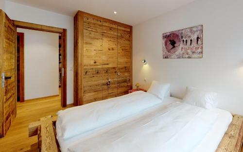 een slaapkamer met een groot wit bed en een houten deur bij Polo in St. Moritz
