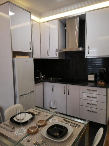 a kitchen with white cabinets and a table with wine glasses at Burgas Termal in Ourense
