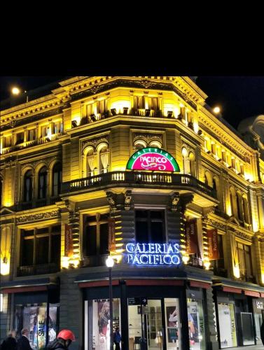 ein großes gelbes Gebäude mit einem Leuchtschild darauf in der Unterkunft Studio Harrods in Buenos Aires