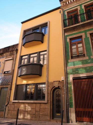 a yellow building with a balcony on a street at 107 Rosario, Guesthouse in Porto