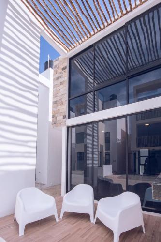 two white chairs sitting next to a building with windows at Hermosos Días Soleados en Villa LUNA DEL MAR in Telchac Puerto