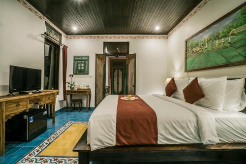 a bedroom with a bed and a desk and a television at Villa Tanah Carik by Mahaputra in Tegalalang