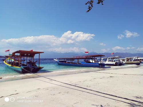 three boats parked on a beach in the water at Kusuka Bungalow in Gili Trawangan