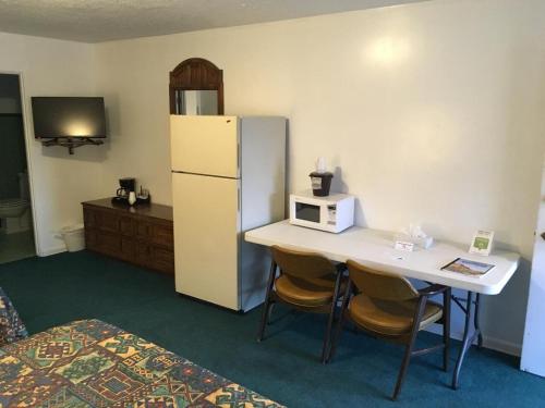 a room with a refrigerator and a table with chairs at Rest Assured Inns & Suites in Montpelier