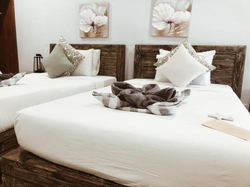 2 camas en una habitación con sábanas y almohadas blancas en Kalua Boutique Bungalows, en Gili Trawangan