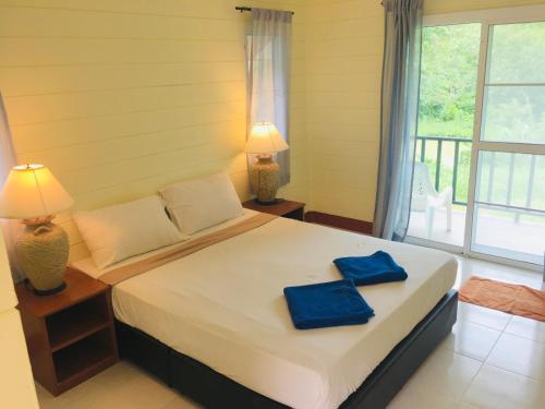 1 dormitorio con 1 cama con 2 toallas azules en Mookies Bungalows, en Ko Mook