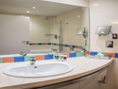 a bathroom with a sink and a large mirror at Mercure London Heathrow Airport in Hillingdon