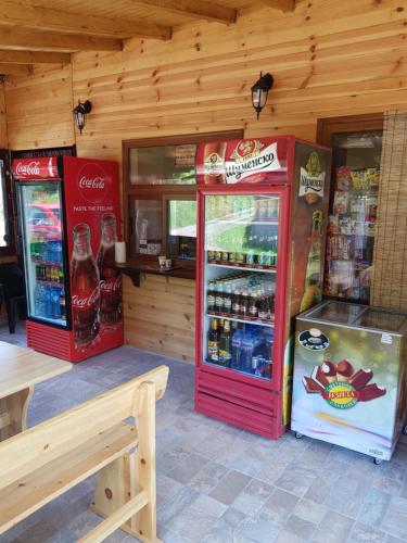 dos máquinas de cocacola en un restaurante con mesa en ЕКО БУНГАЛА, en Trŭn