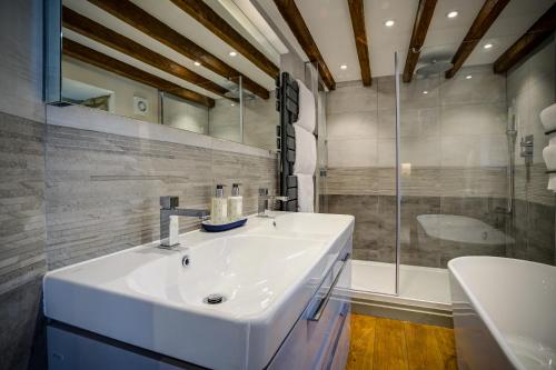 a bathroom with a white sink and a shower at Luxury medieval barn in Cotswold town centre in Fairford