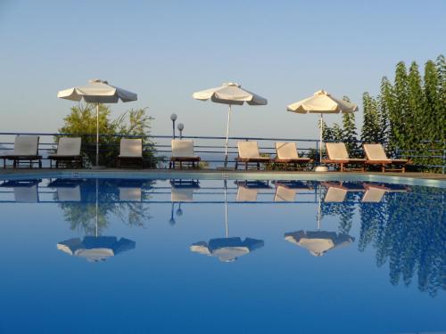 a swimming pool with chairs and umbrellas next to it at Artemis Apartments in Kalyves