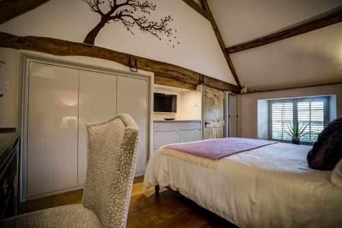 a bedroom with a bed and a chair in it at Luxury medieval barn in Cotswold town centre in Fairford