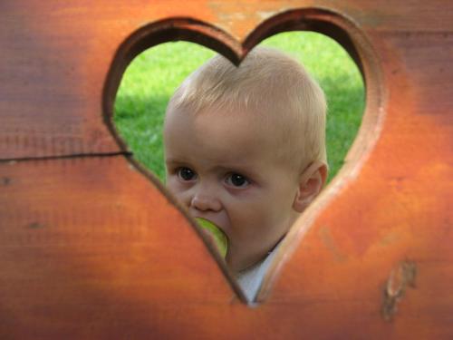 a baby is peeking through a wooden heart at Farm Stay "Alpine Dreams" in Solčava