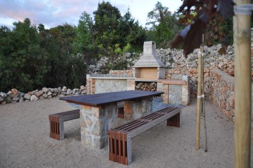 a stone barbecue with a bench and a table at Hotel Kanajt in Punat