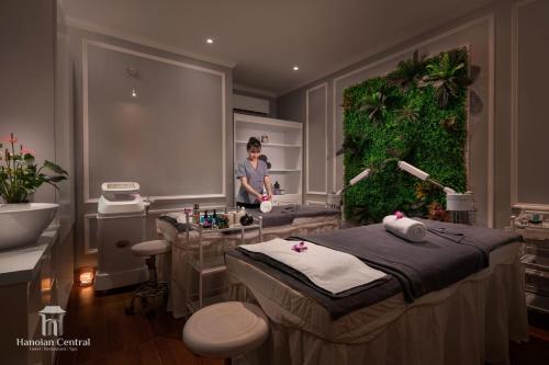 a man standing in a treatment room with a bed at Hanoian Central Hotel & Spa in Hanoi
