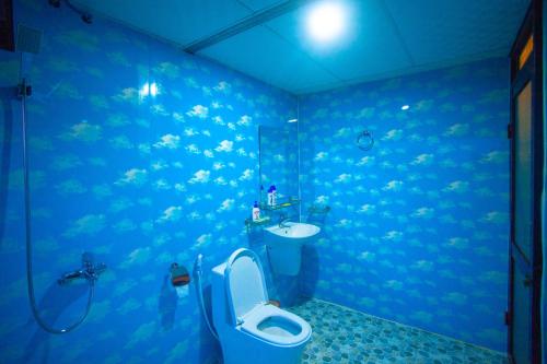 a blue bathroom with a toilet and a sink at Phong Nha Bolero Bungalow in Phong Nha