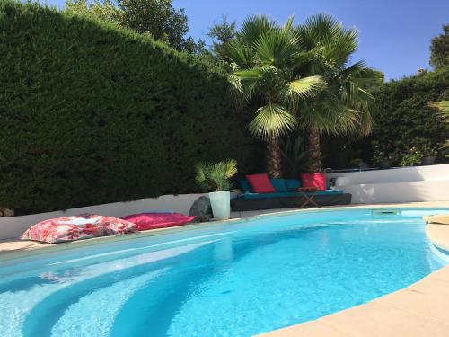 a large swimming pool with pillows and palm trees at Bed,Kitchen and Swimming Pool Villa Esterel in Saint-Raphaël