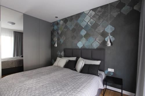 sypialnia z białym łóżkiem i szarą ścianą w obiekcie Apartament Gardenia Sea&Sun DZIWNÓW PRZY PLAŻY w Dziwnowie