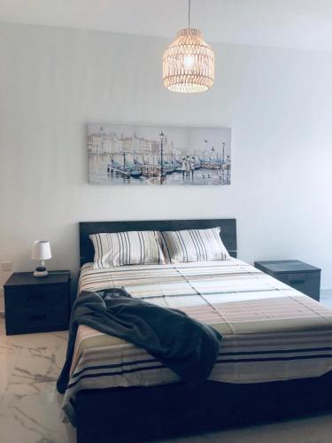 a bedroom with a large bed with a chandelier at Brand new Mellieha sea view apt with parking in Mellieħa