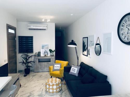 a living room with a couch and a clock on the wall at Brand new Mellieha sea view apt with parking in Mellieħa