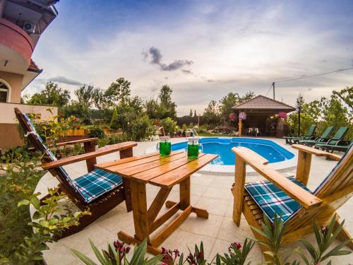 a wooden table and chairs next to a swimming pool at Villa Katarina with pool in Banja Luka