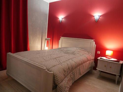 a bedroom with a bed with red walls and two lights at Les Rosiers d'Y in Nevers