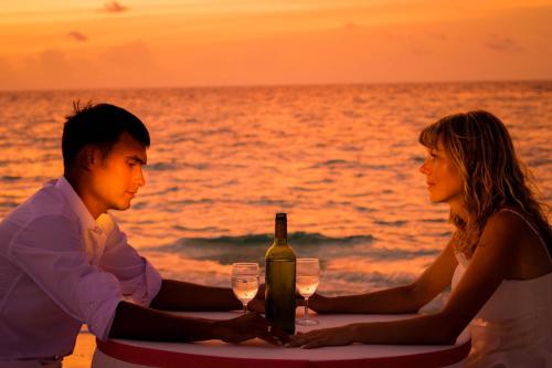 mężczyzna i kobieta siedzący przy stole z butelką wina w obiekcie Summer Villa Guest House w mieście Maafushi