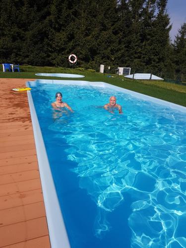 dos hombres en una piscina con un frisbee en Zagroda Cztery Wiatry, en Sądry