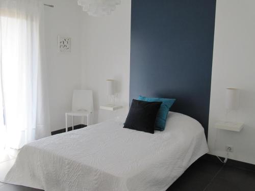 - une chambre avec un lit blanc et un mur bleu dans l'établissement T2 de standing idéalement situé, à Propriano