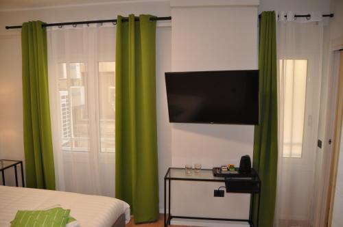 a bedroom with green curtains and a flat screen tv at EVA LUXURY ROOMS CAGLIARI in Cagliari