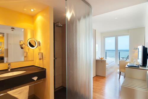 a bathroom with a sink and a large mirror at Strandhotel Georgshöhe in Norderney