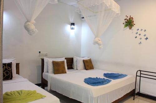 two beds in a room with white walls at Sigiri Saman Home Stay in Sigiriya
