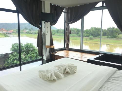 a bedroom with a bed with a view of a river at Nava Tara Resort in Takua Pa