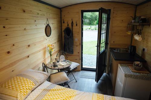 a bedroom with a bed and a table and a kitchen at Buttles Shepherd's Hut in Saundersfoot