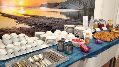 un tavolo con piatti bianchi e cibo sopra di Case Vacanze Ancora a Porto Empedocle