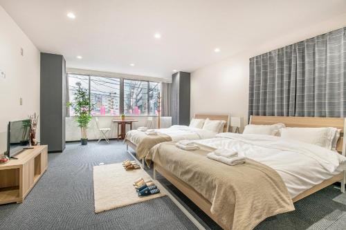 a bedroom with two beds and a flat screen tv at Uhome Ueno Apartment 4 in Tokyo