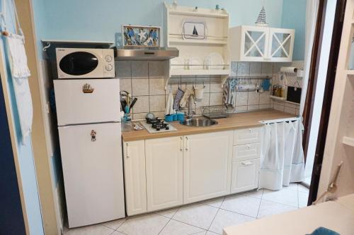 a kitchen with a white refrigerator and a sink at Blue sea in Aci Castello
