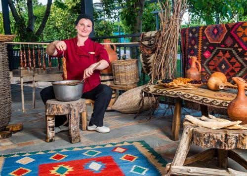 a man sitting on a bench stirring a pot at Ambassadori Kachreti Golf Resort in Kachretʼi