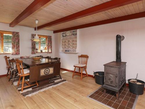 12 person holiday home in L s في Læsø: غرفة معيشة مع موقد خشبي وطاولة