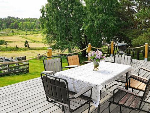 6 person holiday home in VAREKIL في Varekil: طاولة مع كراسي و إناء من الزهور على سطح السفينة