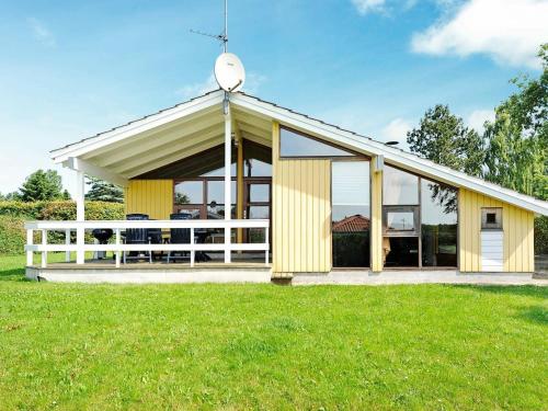 a yellow house with a white fence in a field at Secluded Retreat with Sauna - By Traum Ferienwohnungen in Sønderby