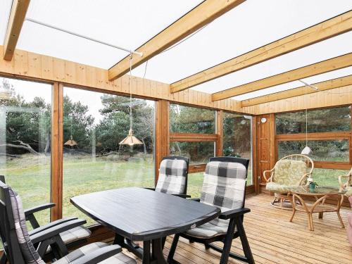 a screened in porch with a table and chairs at Comfortable Holiday Home in Vejers Strand with Terrace in Vejers Strand